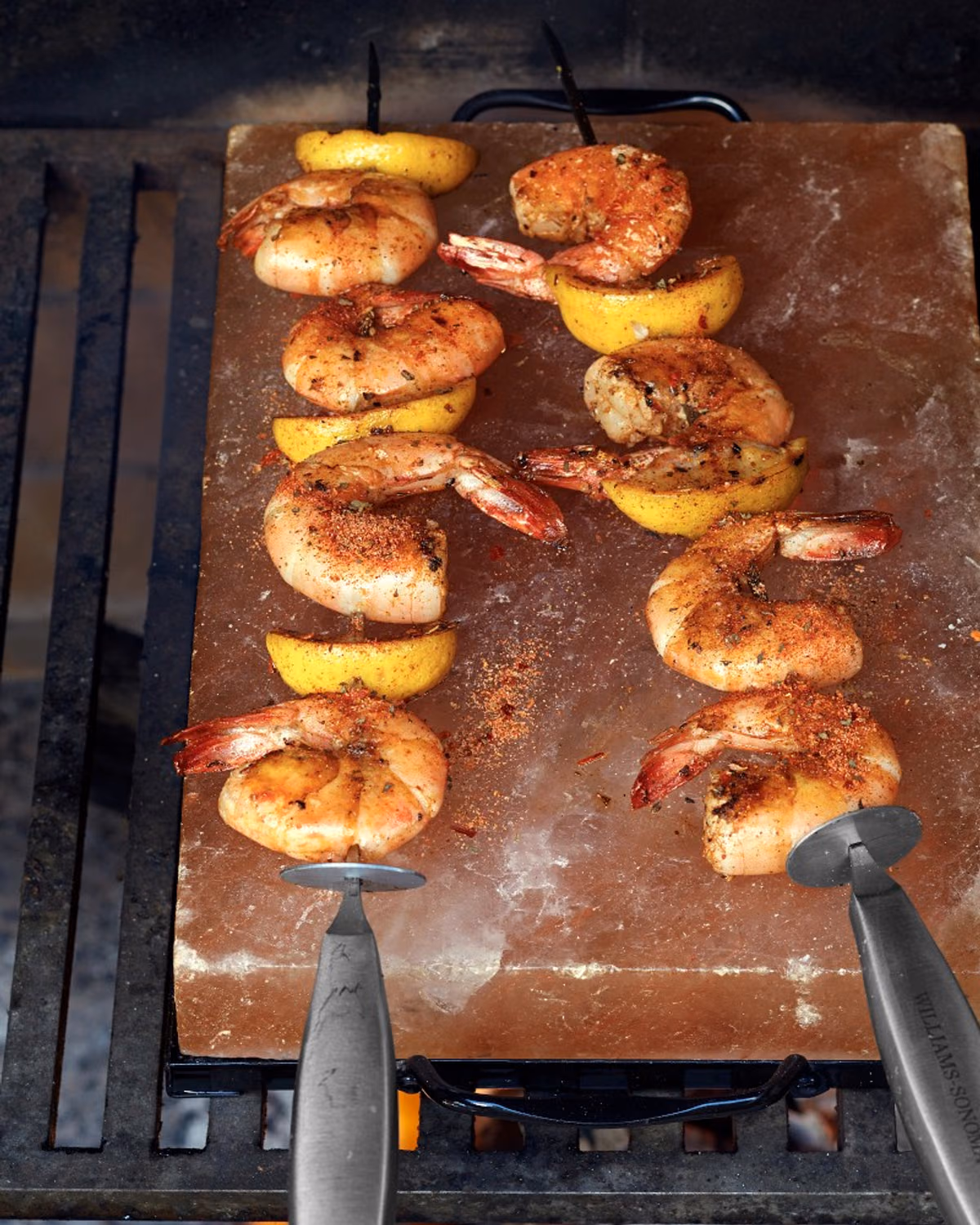 Shrimp and lemon cooking on a salt plate over a grill