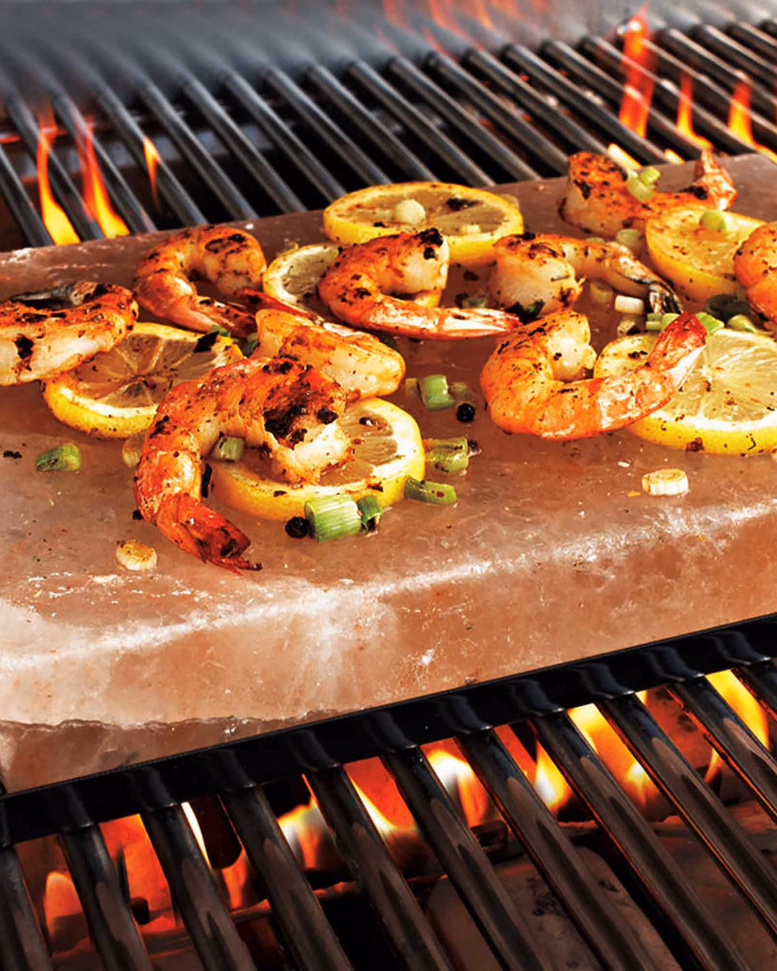 Shrimp and lemon cooking on a pink salt plate over a grill